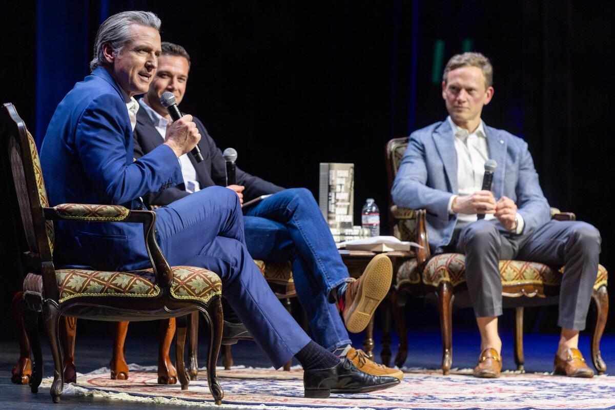 Gavin Newsom, Jon Favreau and Tommy Vietor sitting on stage