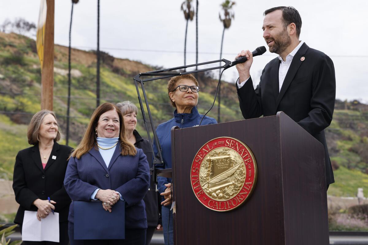 A man speaks behind a lectern as people watch him.