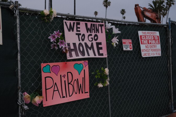  Former residents have hung signs on the chain-link fence outside the Palisades Bowl mobile home park. 
