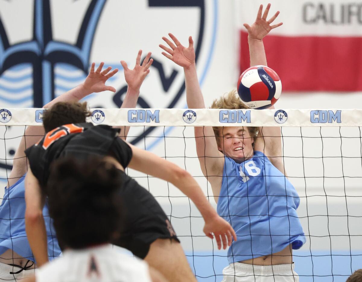 Corona del Mar's Jack Robinson (16) blocks a kill attempt from Huntington Beach's Logan Hutnick (21).