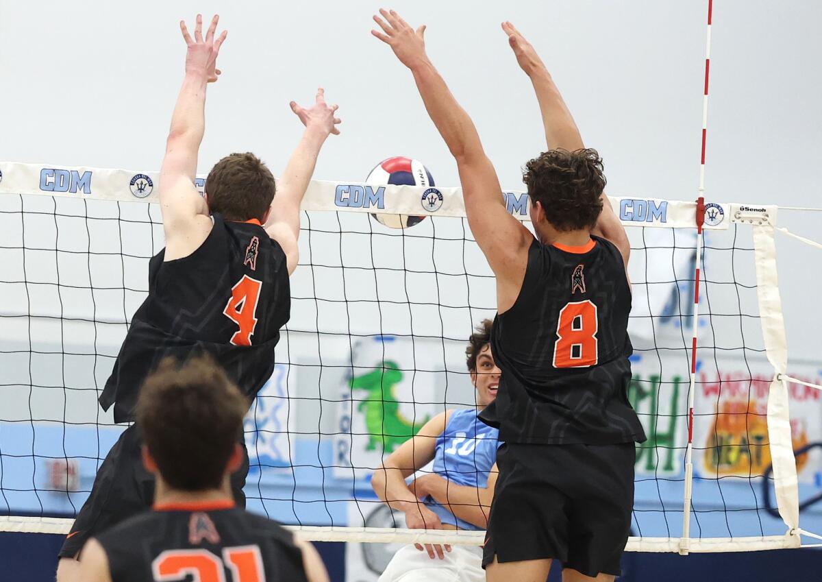 Huntington Beach's Ben Arguello (8) blocks a kill with help from Lucas Brazao (4) on Corona del Mar's Hunter Hanneman (10).