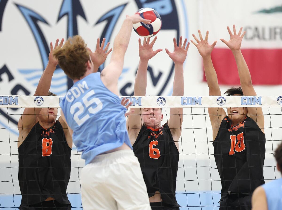 Huntington Beach's Ben Arguello (8), Kenno Kosty (6) and Colin Choi (10) put up a triple block against CdM's Brady Gant (25).