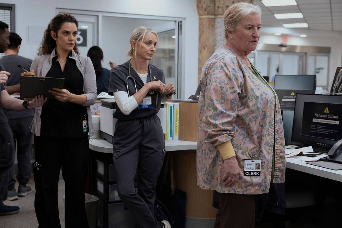 Three women stand near a counter with computer screens.