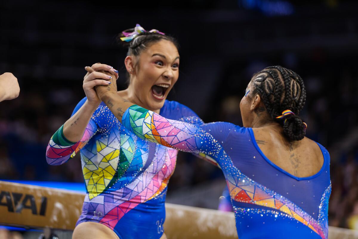 UCLA gymnast Ciena Alipio celebrates with teammate Jordan Chiles after completing a beam routine.