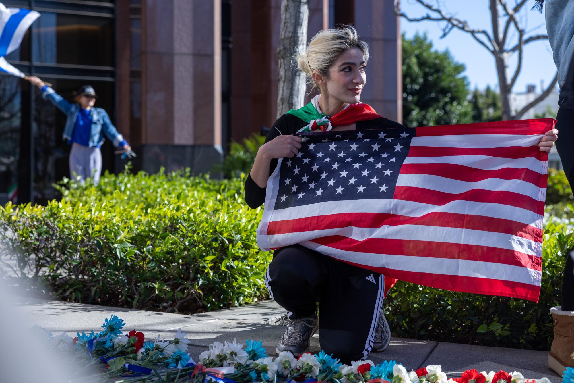 Influencer Charlene Laurent waves an American flag in front of the Consulate General Israel.