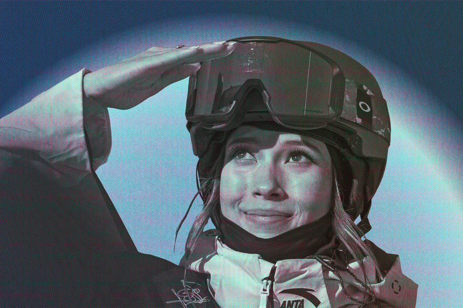 A person wearing a ski helmet and jacket looks up with a slight smile, shielding their eyes with one hand against the sun.