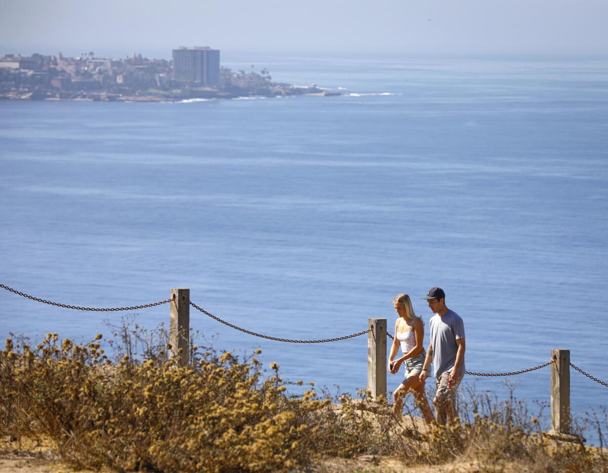 Two people walk up the path from Black's Beach in La Jolla.