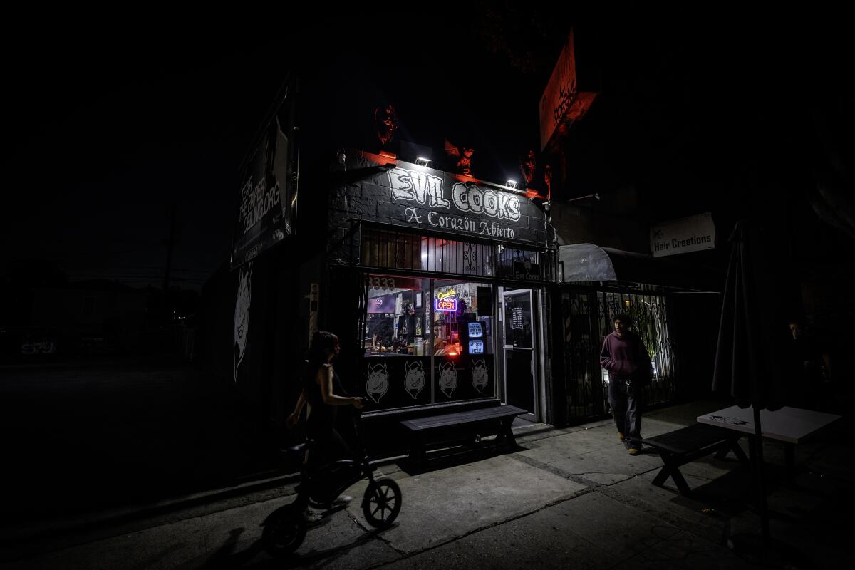 Pedestrians walk by restaurant "Evil Cooks" in the El Sereno neighborhood of Los Angeles
