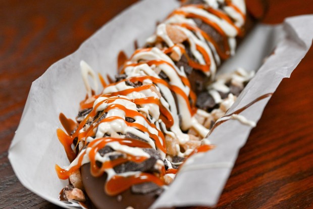 Frozen Banoffee Banana; Milk chocolate-dipped frozen banana with toffee pieces, caramel sauce and white chocolate drizzle at Clarabelle's Hand-Scooped Ice Cream on Buena Vista Street during the California Food & Wine Festival inside California Adventure running March 6 through April 27, 2026. Photographed on Friday, March 6, 2026. (Photo by Jeff Gritchen, Orange County Register/SCNG)