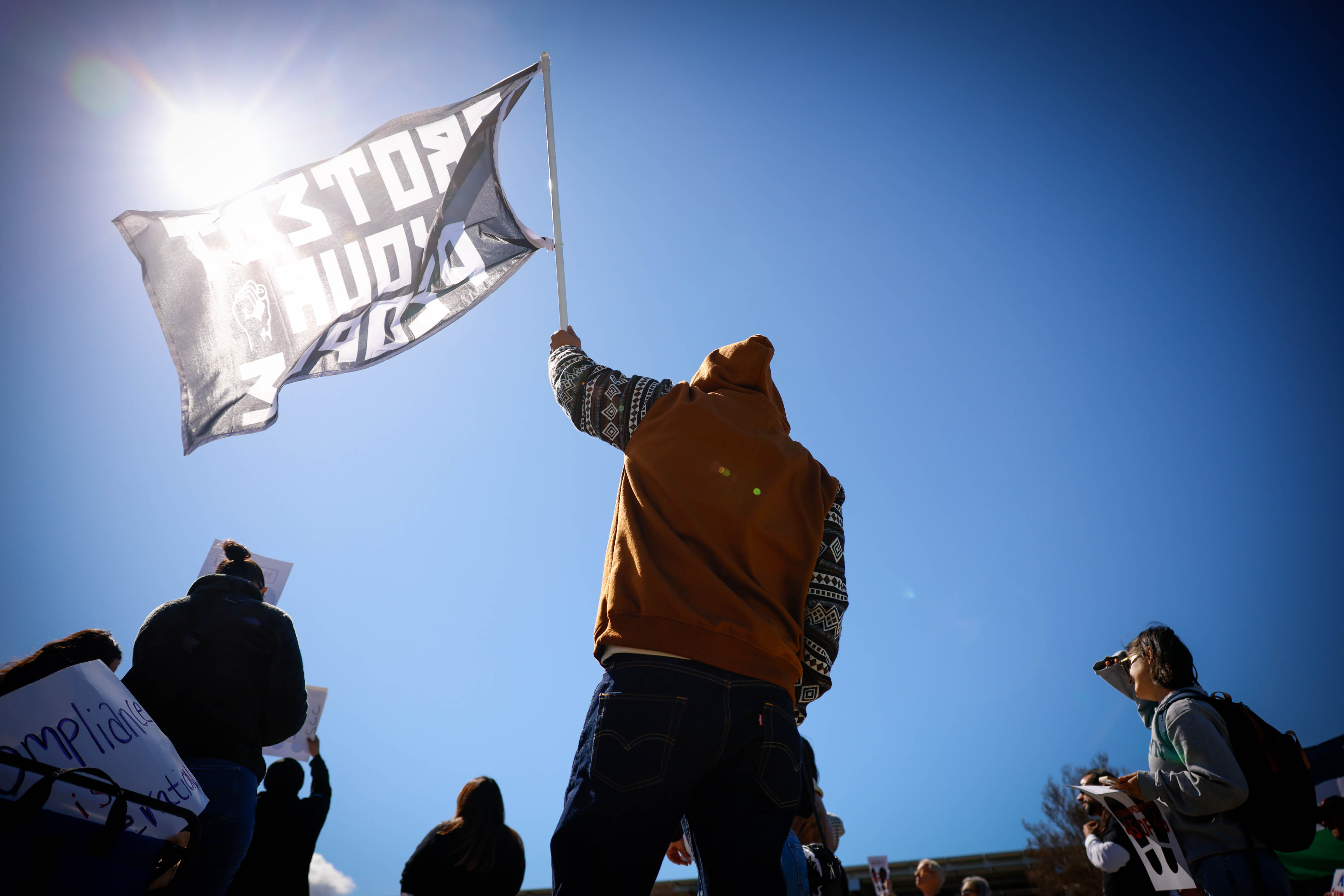 A person waves a flag that says âprotect the peopleâ...