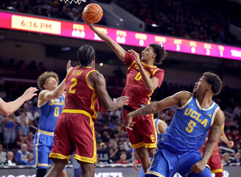  USC guard Alijah Arenas scores over UCLA guards Trent Perry, left, and Brandon Williams.