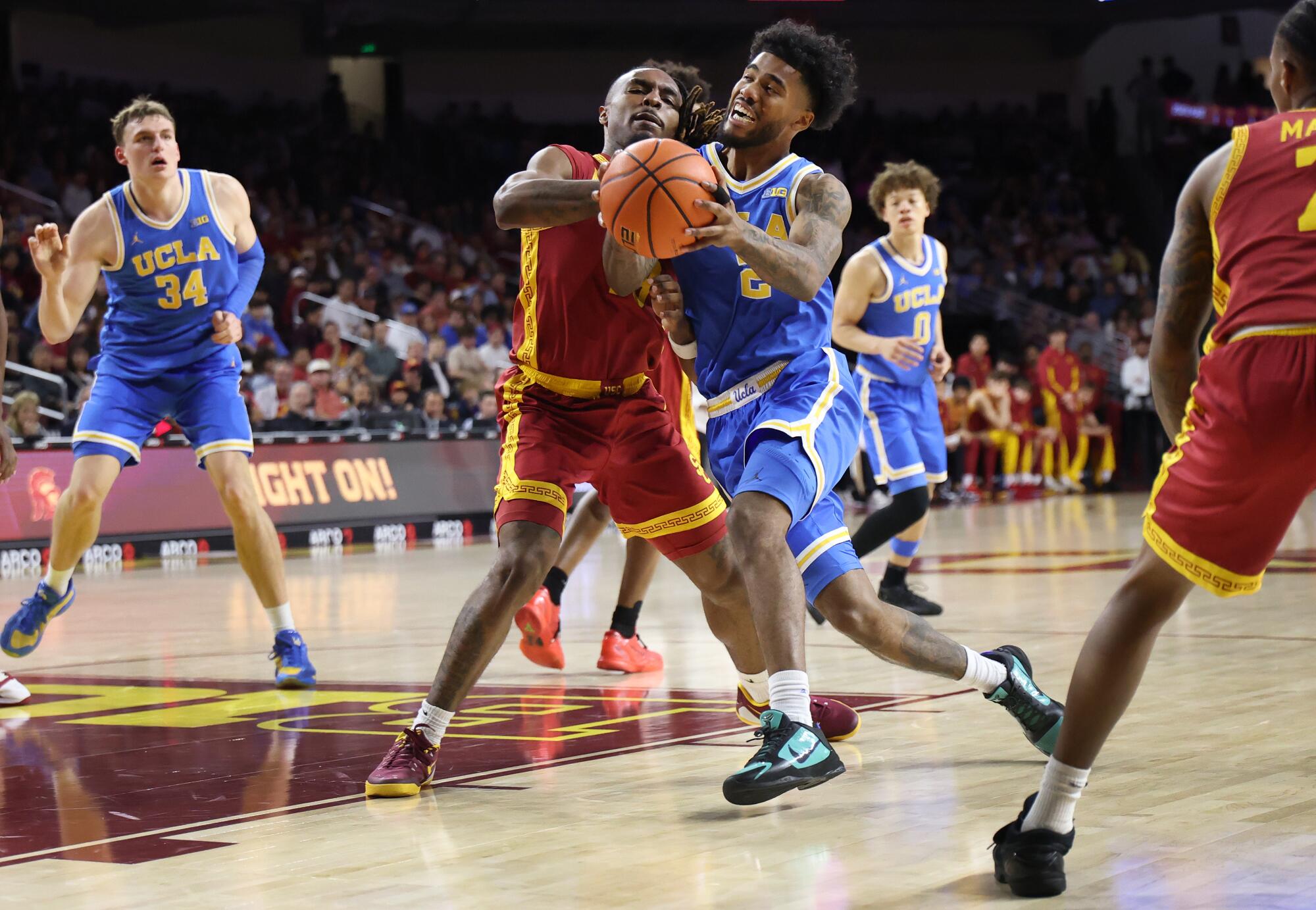 UCLA guard Donovan Dent drives to the basket in front of USC guard Kam Woods during the second half Saturday.