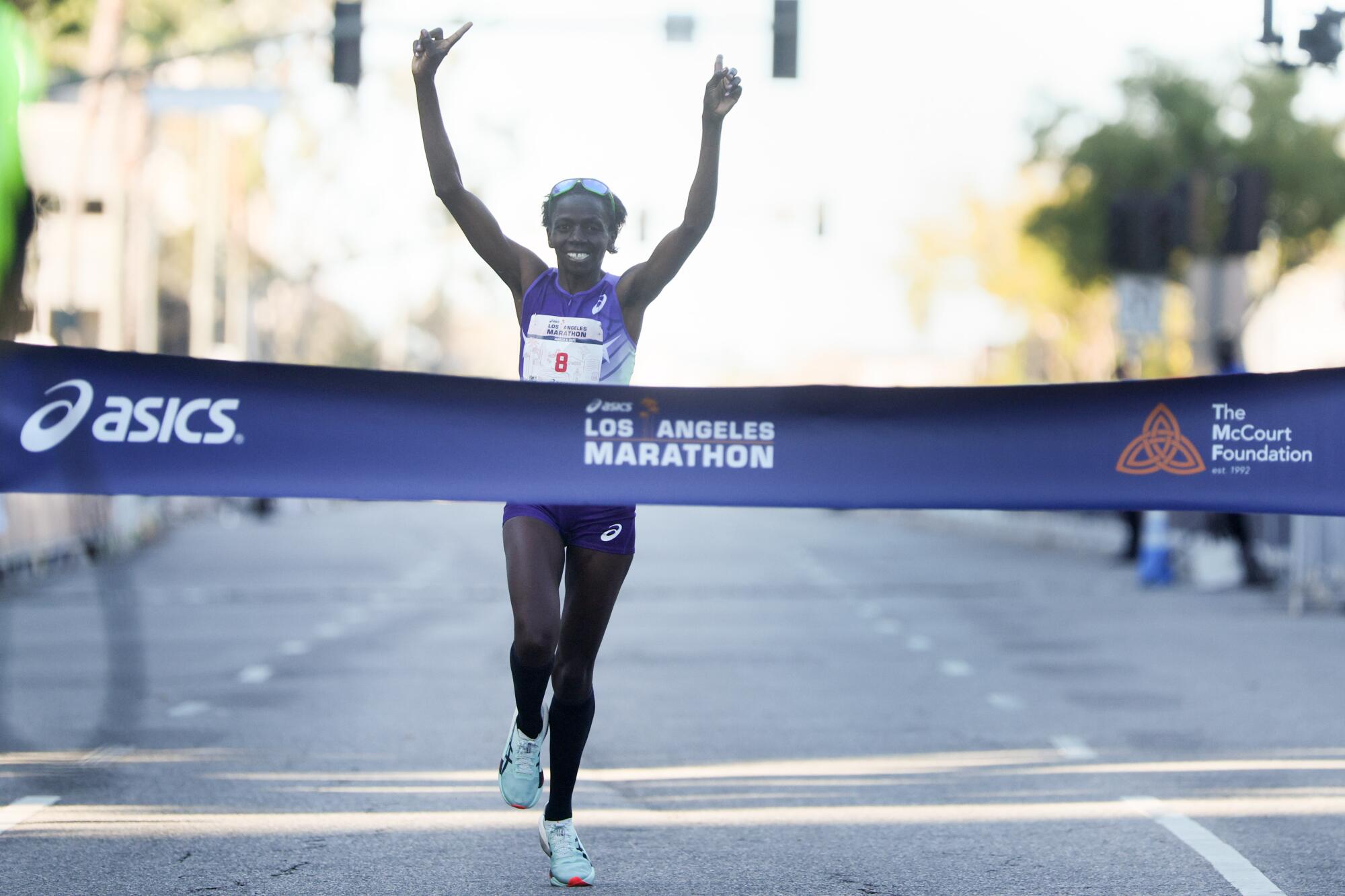 Kenyan Priscah Cherono waves her hands in the air as she wins the women’s elite race during the L.A. Marathon on Sunday.