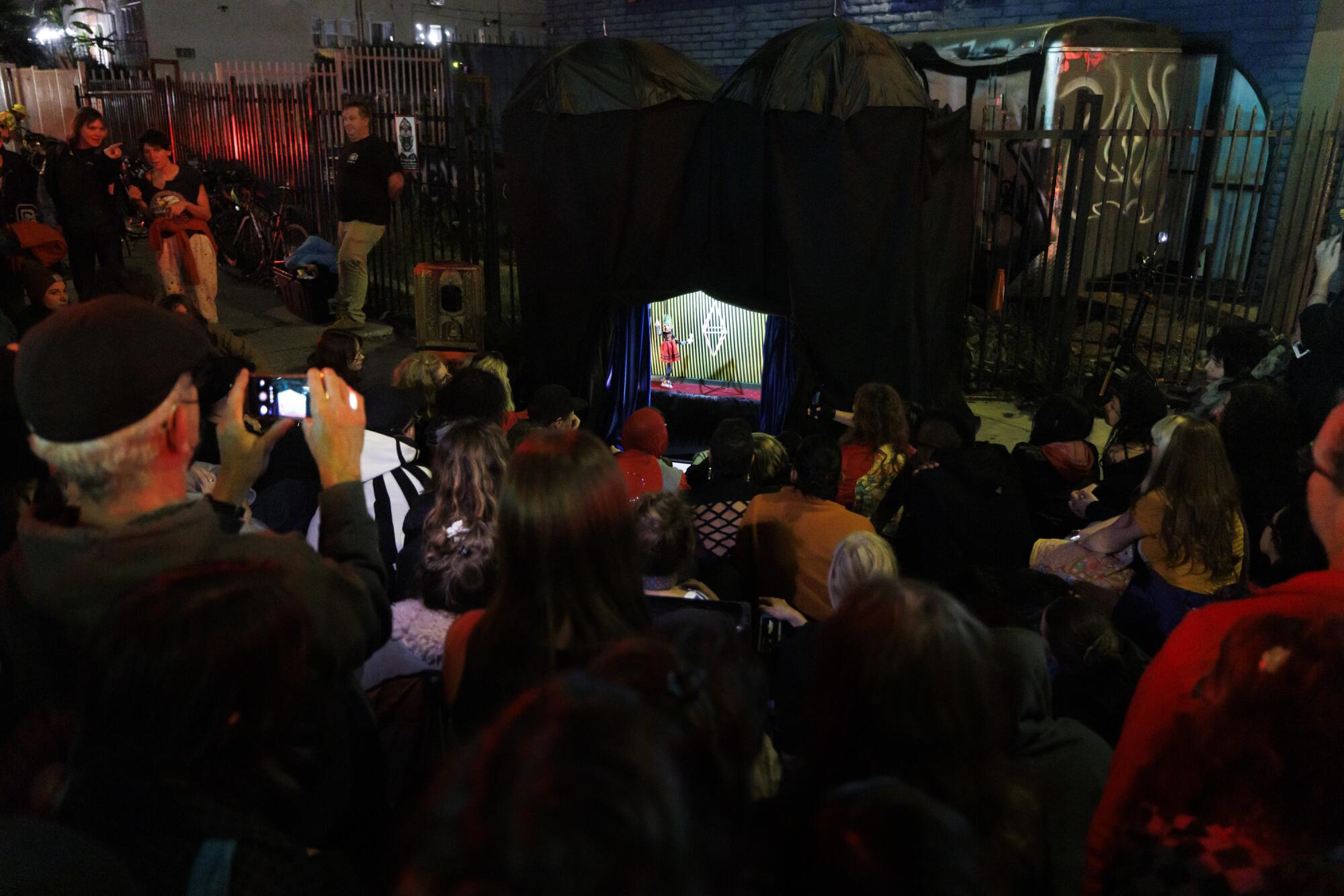 People gather around a puppet stage.