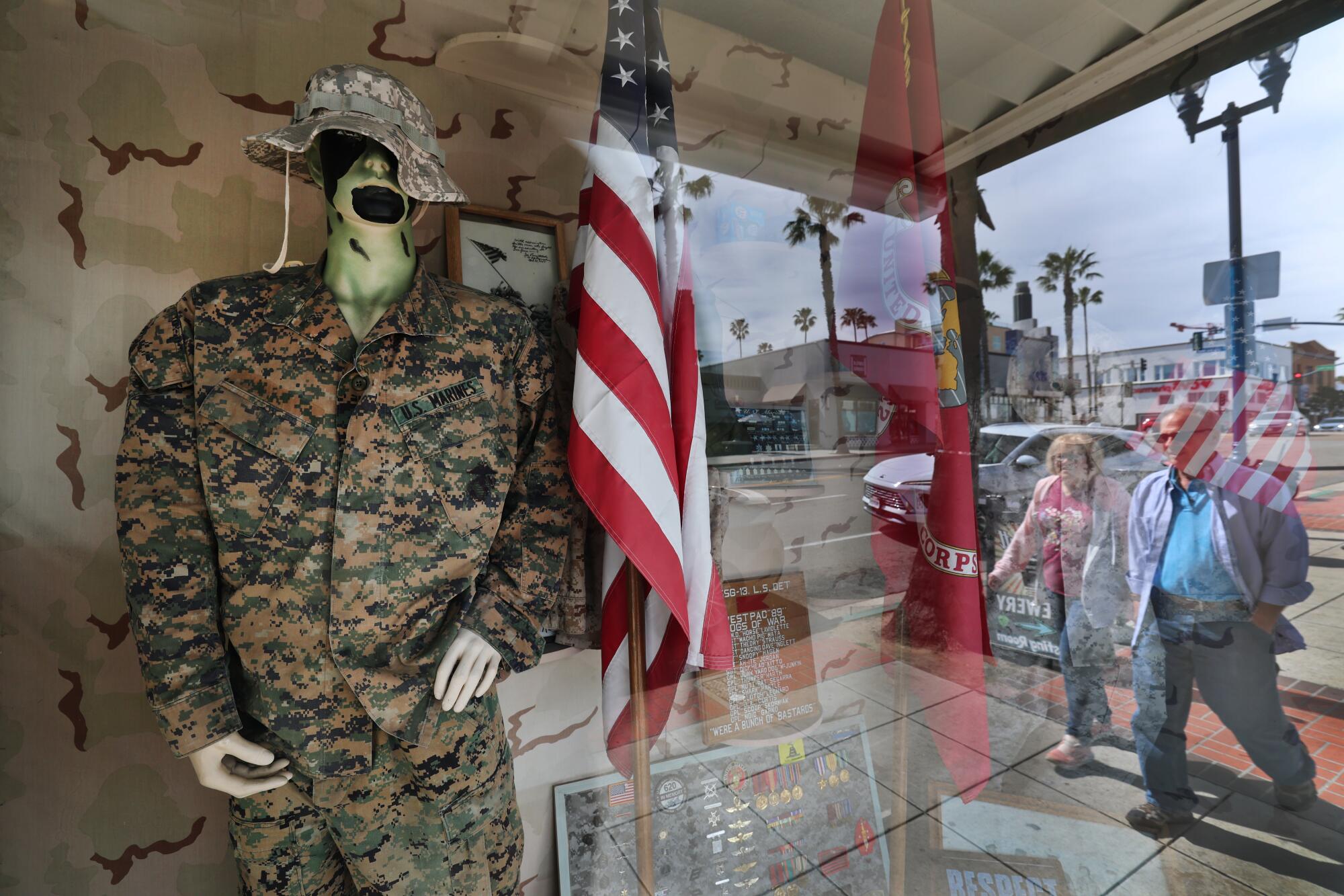A mannequin wears camouflage fatigues in a store window. 