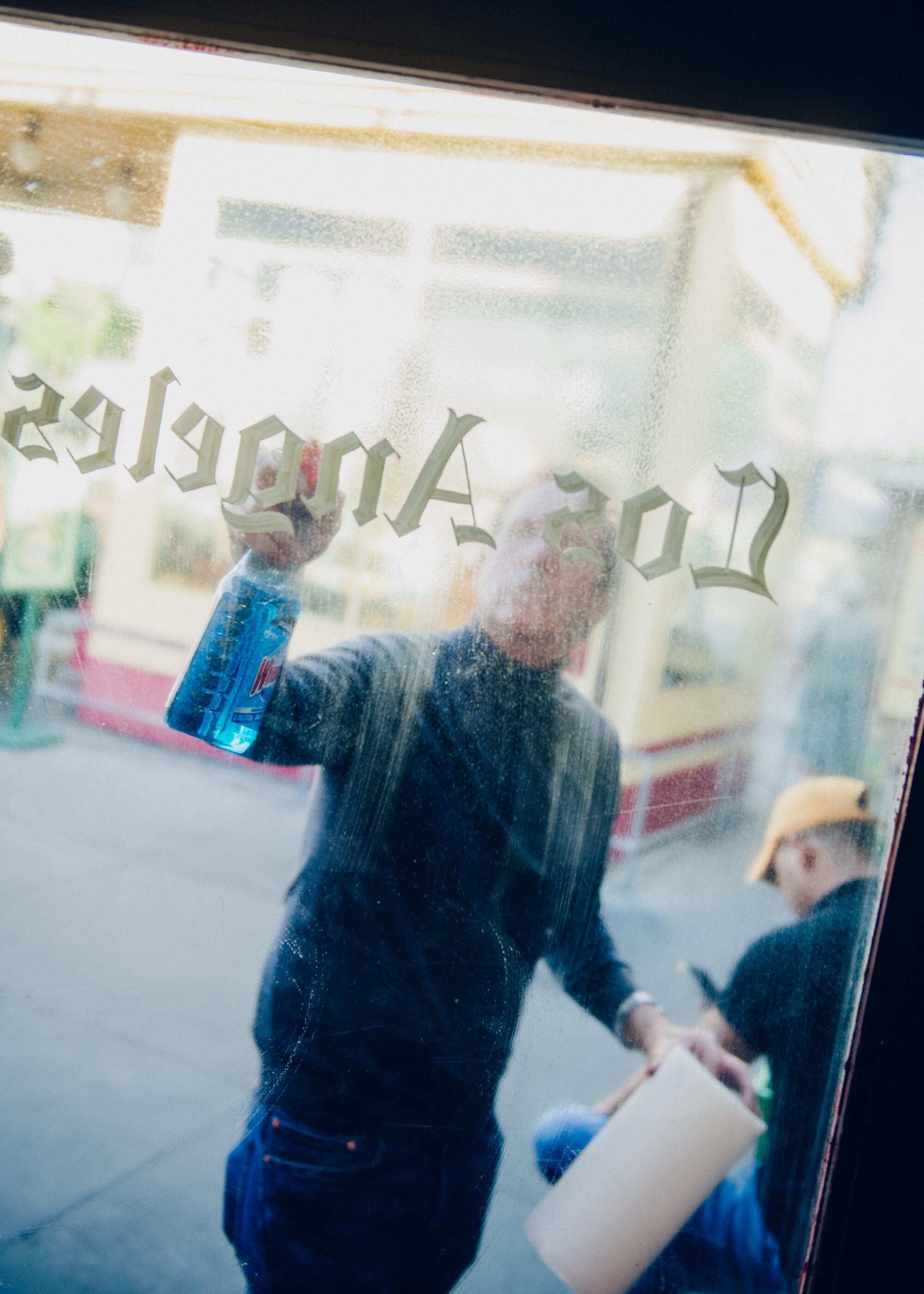 Paul Sobel cleans a glass door of the newsstand.
