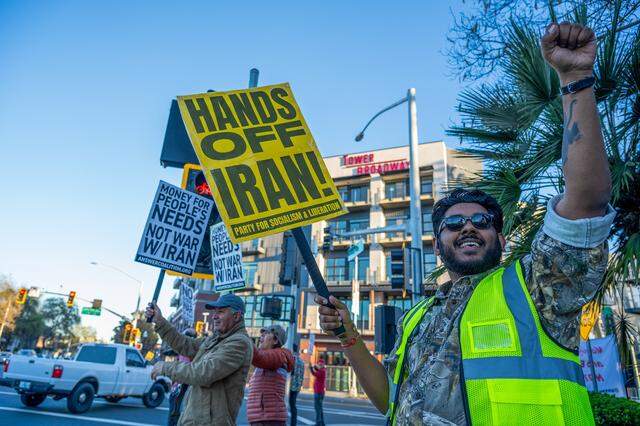 Kunaal Kumar holds up his fist at the corner of 16th Street and Broadway in Sacramento on Monday while demonstrating against the U.S.-Israel war with Iran.