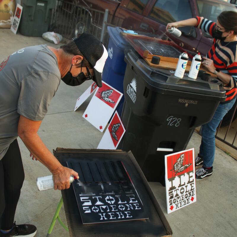 Tina Silva, left, an IC4IJ activist and local retiree, paints the signs. Silva said the ICE raids in LA over the summer prompted her to "wake up to what was happening to my neighbors," on Saturday, Dec. 13, 2025 in Ontario , CA.