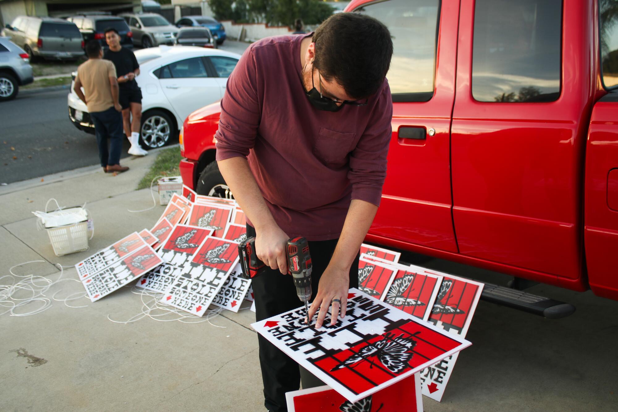 Michael Rios drills holes into signs.