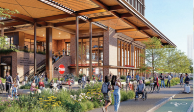 People walk, sit, and bike outside a modern, multi-story Caltrain San Francisco station with large windows and greenery.
