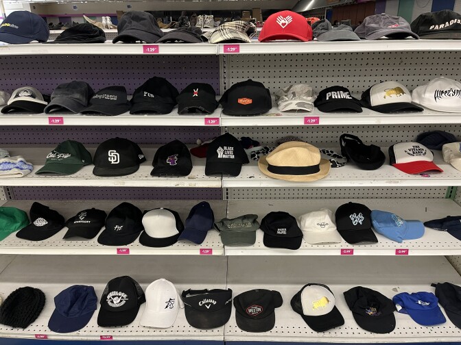 A display of many different kinds of hats on white store shelves.