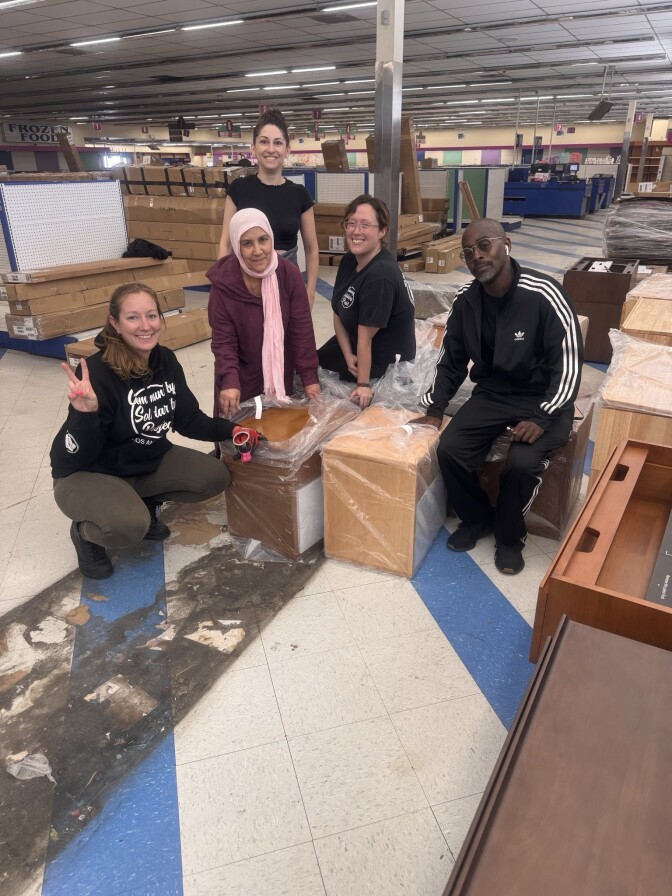 Five people pose for a picture in the middle of a retail space.