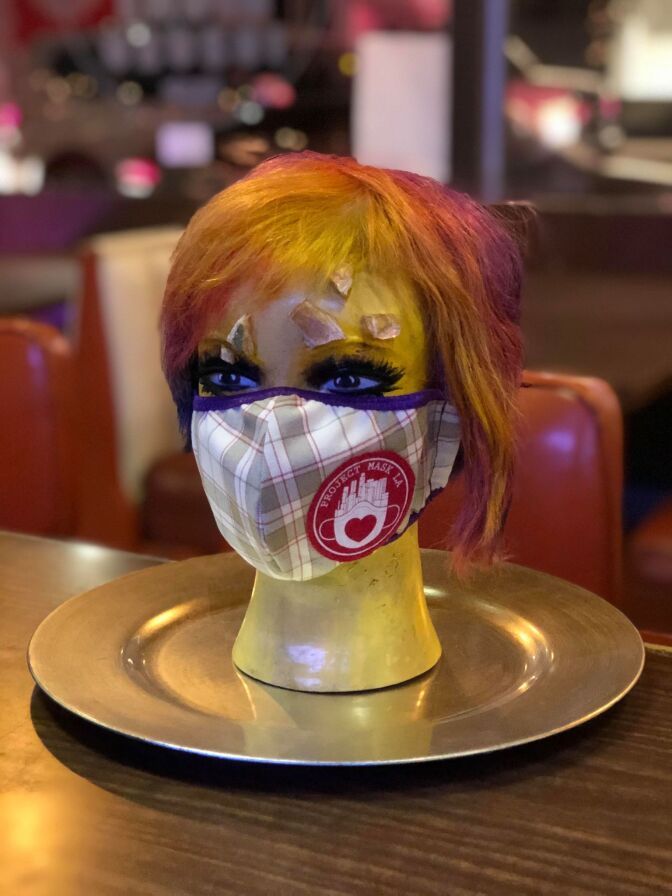 A mannequin head with a multicolored wig, eye makeup and a mask on.