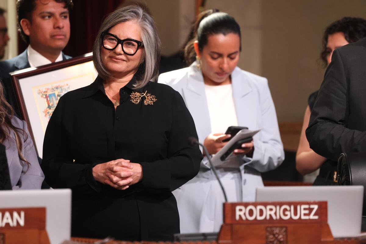 A standing woman smiles, with people standing behind her.