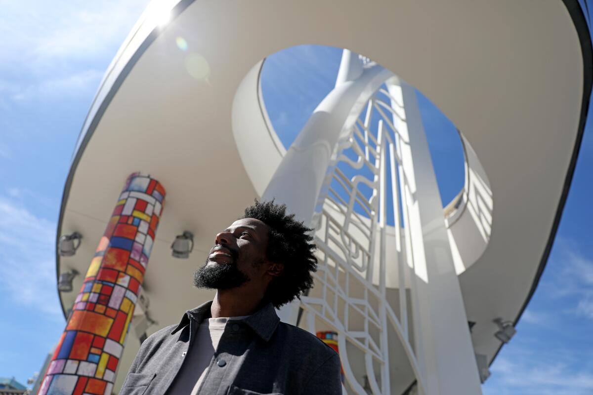 A man poses in front of a tower in Downtown Disney that nods to Black history