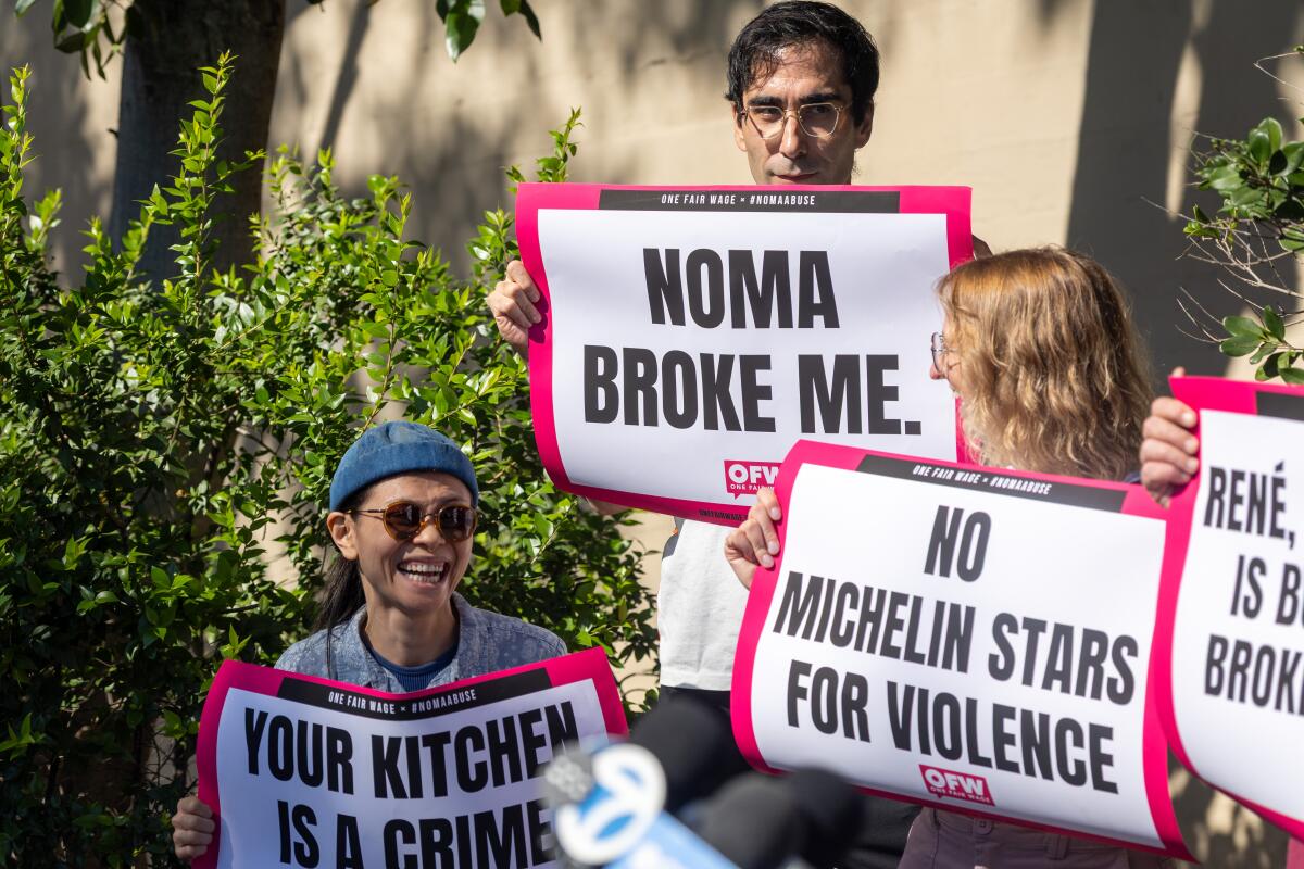 Former Noma employee Jason Ignacio White, center, holds a sign saying "Noma broke me" during a protest 