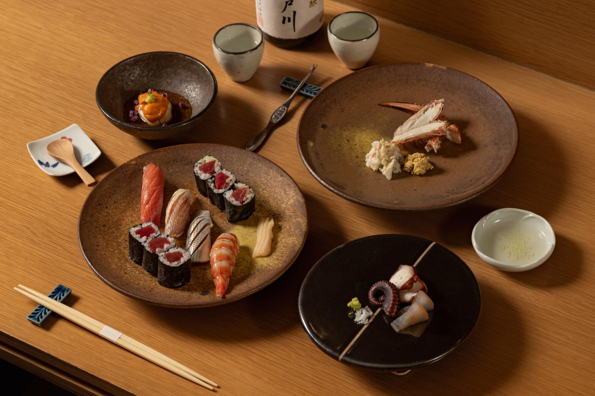 A selection of dishes including an assortment of nigiri, maki and appetizers with sake at Osusume Fumio in L.A.