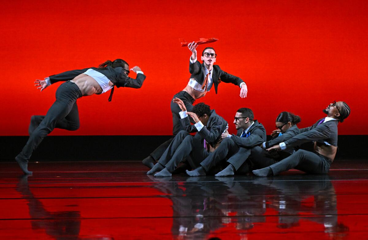 Dancers in suits on a red stage.