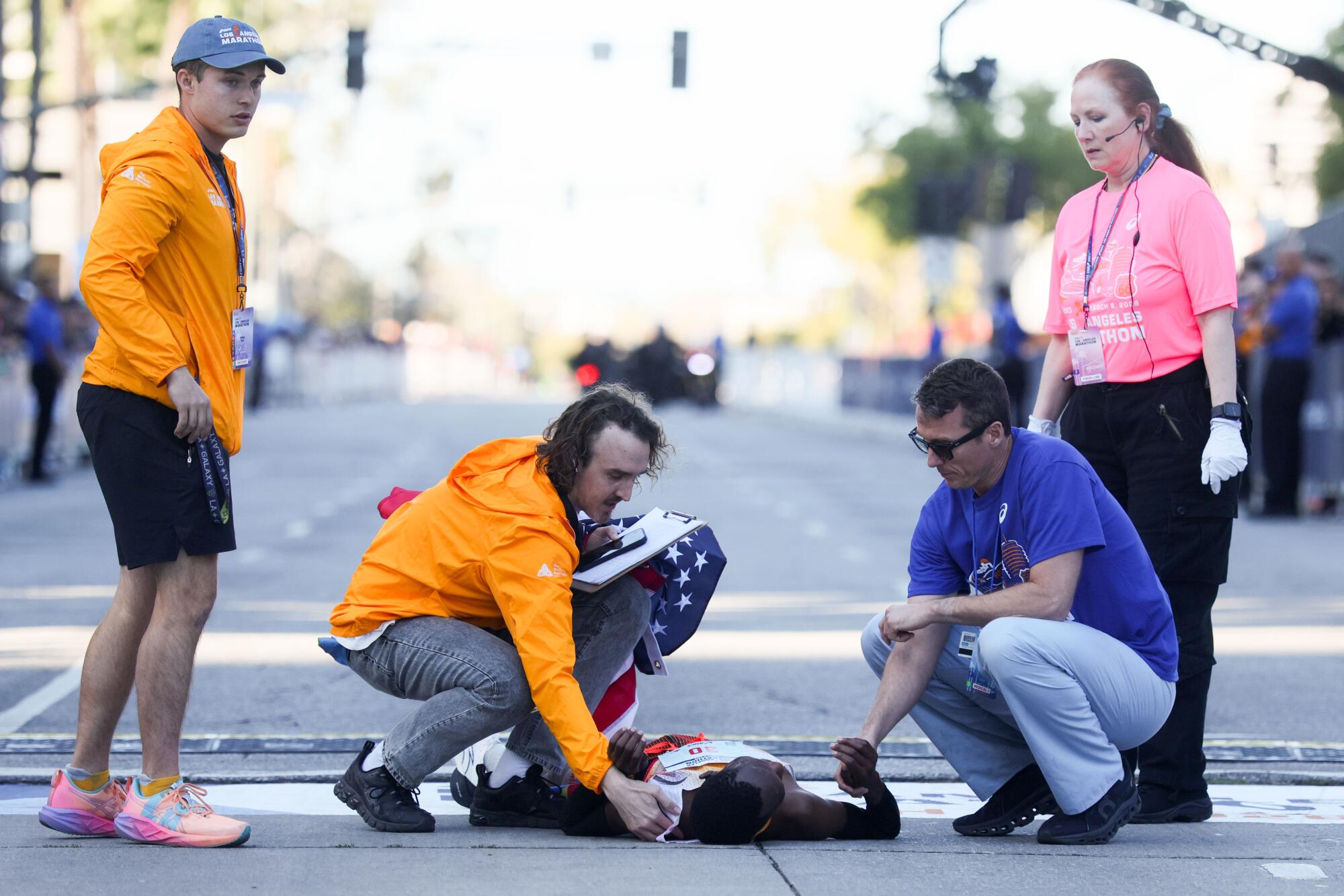 Kenya's Michael Kimani Kamau is tended to by race personnel after falling at the finish line during the L.A. Marathon.