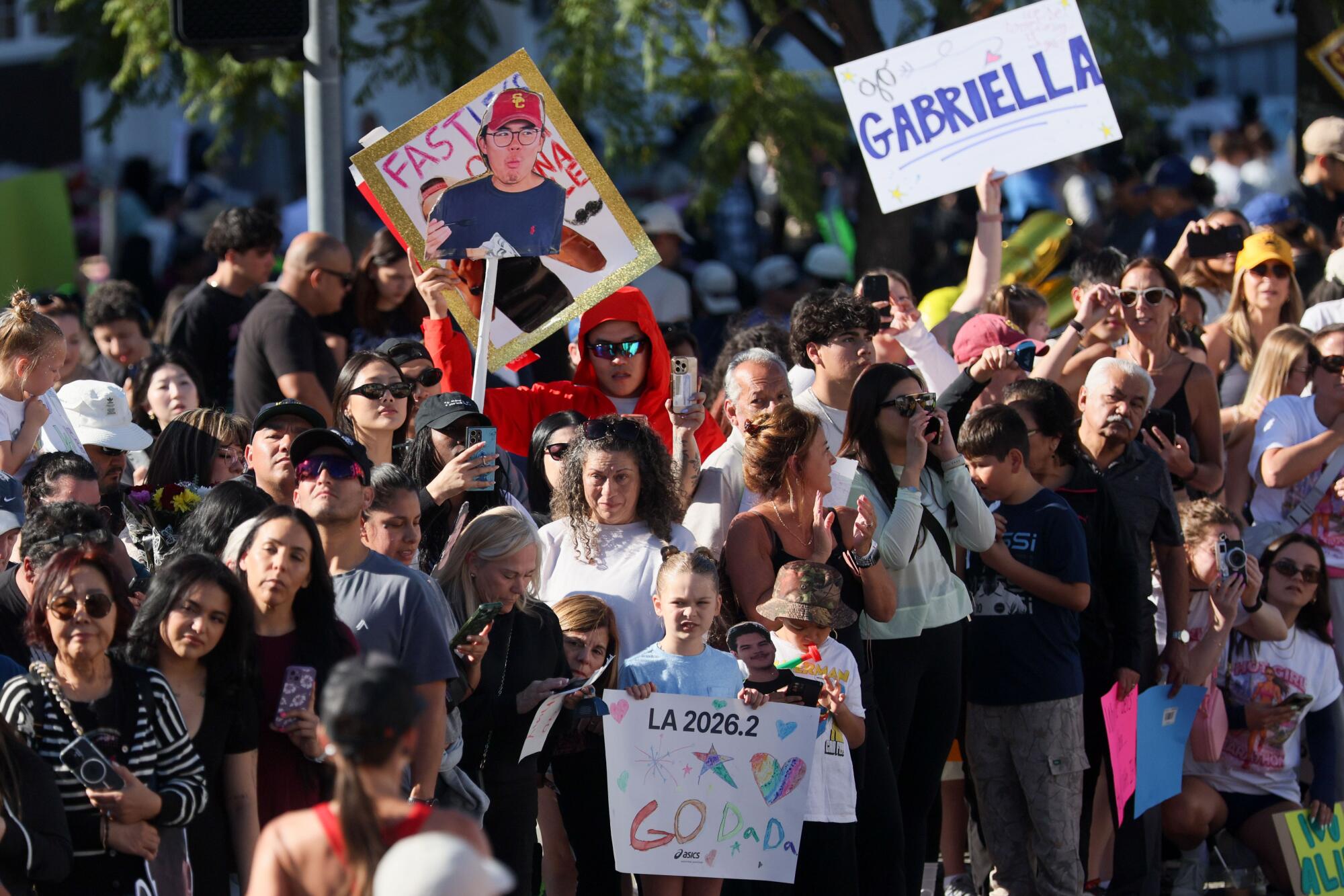 Spectators watch and hold signs supporting participants at the finish line of the L.A. Marathon on Sunday.