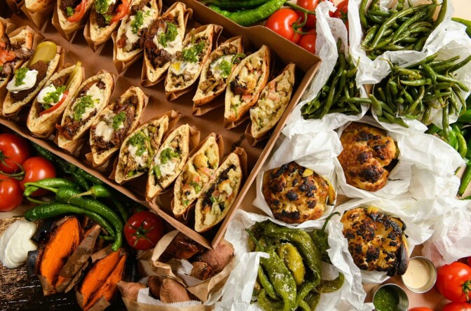 A large assortment of stuffed pitas, roasted cauliflower, green beans and other vegetables.