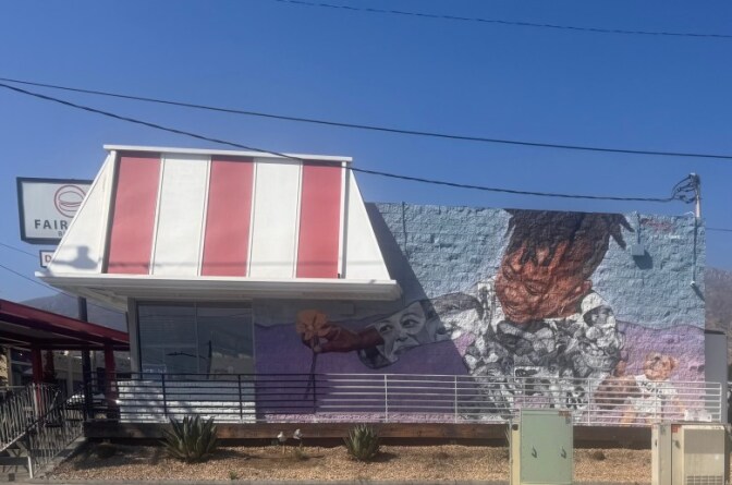 A building with a mural of a small boy with dreadlocks. A large red and white striped awning hangs from the building