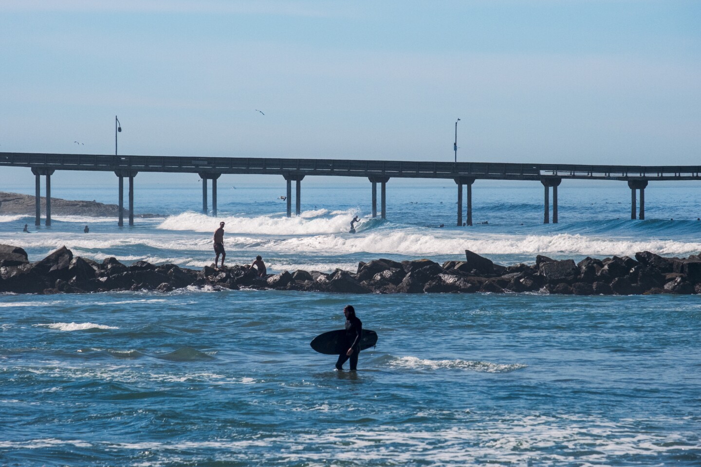 A surfer walks out of the water in Ocean Beach during a winter heat wave, San Diego, March 13, 2026.