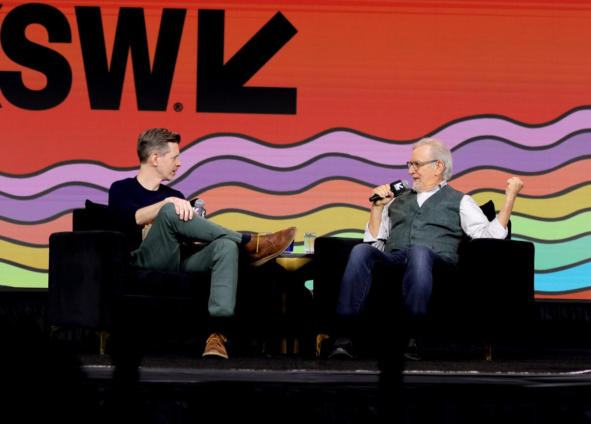 Two men have a conversation on stage at a film festival.