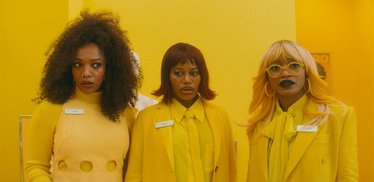 Three women in yellow stand in a yellow room.