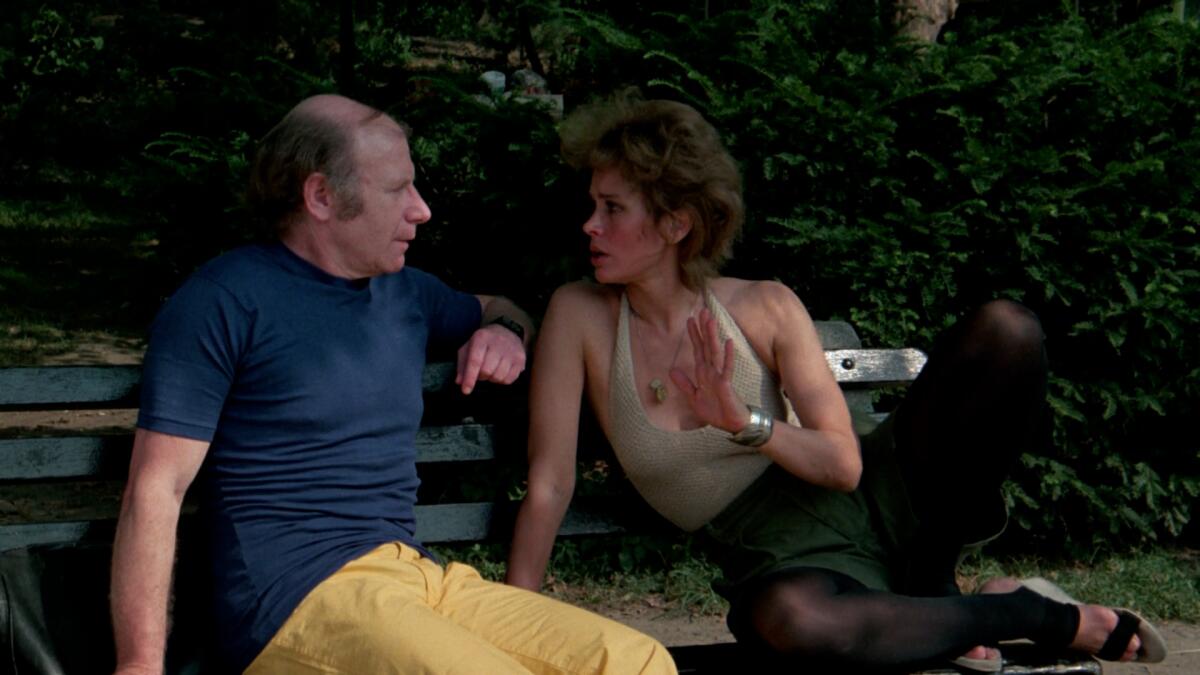 Two people have a conversation on a park bench.