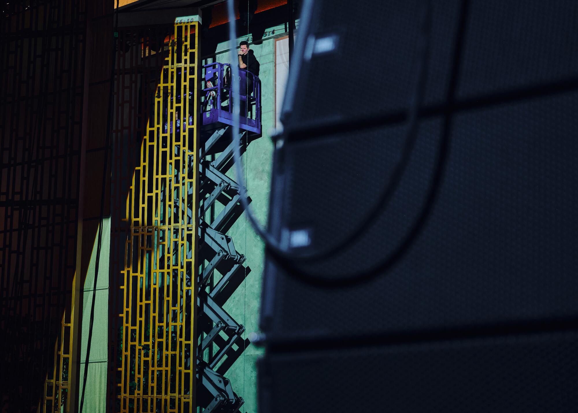 A man works from a tall rig on the inside of the theater. 