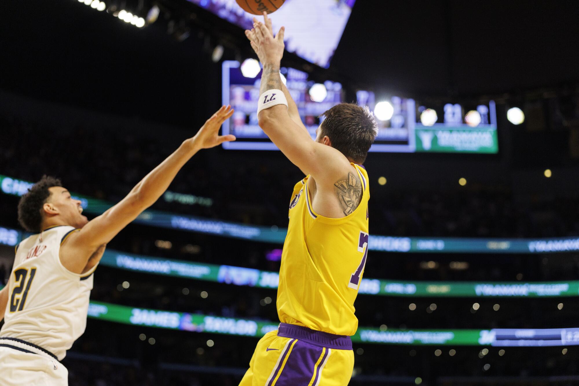 Lakers star Luka Doncic scores the winning basket over Denver Nuggets forward Spencer Jones in overtime Saturday.