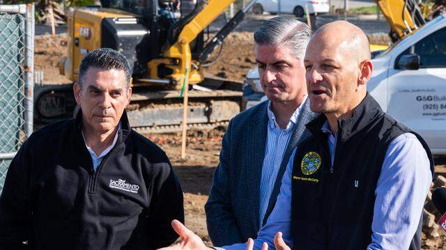 Sacramento Mayor Kevin McCarty, right, speaks as workers build a new safe camping site in the River District on Friday, Feb. 27, 2026. Department of Community Response Director Brian Pedro, left, and Council Member Phil Pluckebaum, center, joined him at the event.