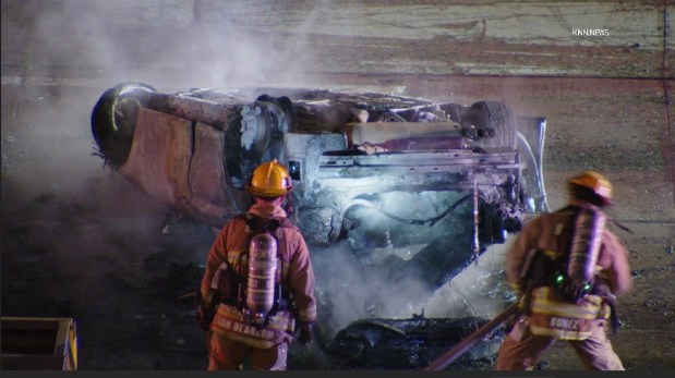Firefighters extinguish a fire in a car that was part of a collision and overturned on the 110 Freeway early Sunday, March 15, 2026. (KNN)