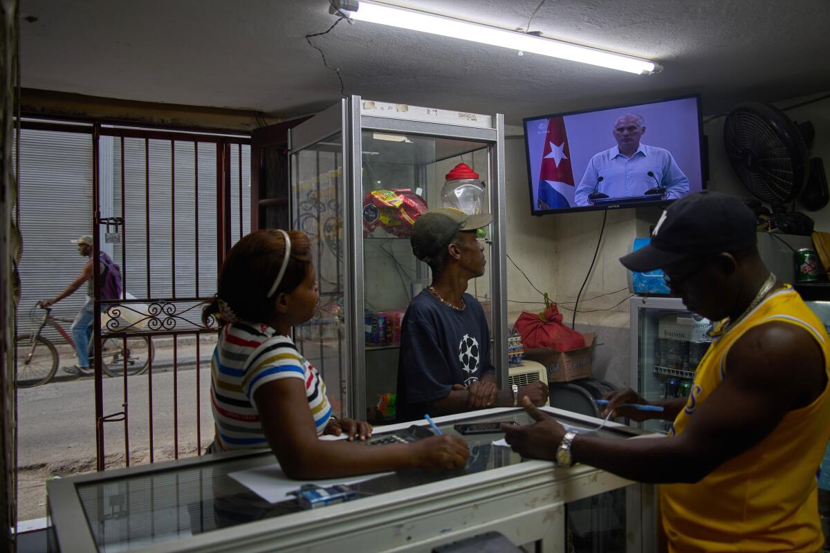 People inside a convenience store watch a TV.