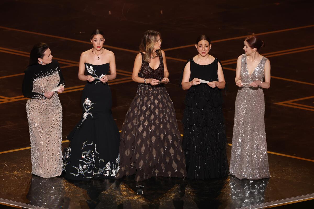 Melissa McCarthy, Rose Byrne, Kristen Wiig, Maya Rudolph and Ellie Kemper standing on stage in gowns