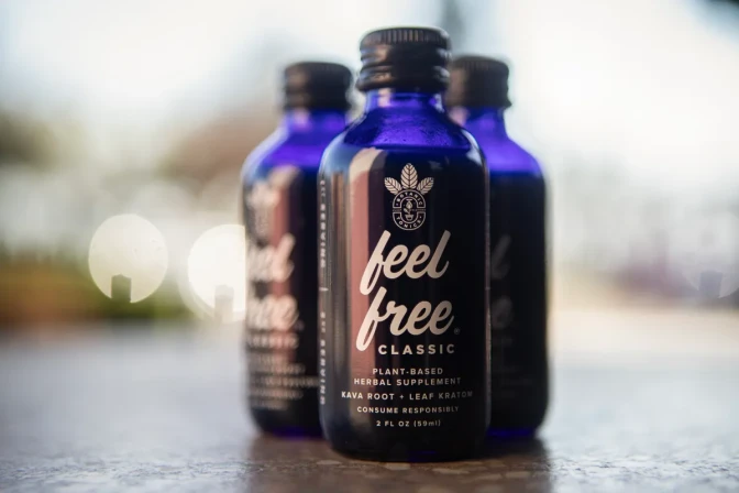 Three small dark blue bottles with text that reads "Fee Free. Classic." are set on a surface. The closest bottle in the foreground is the only one in focus.