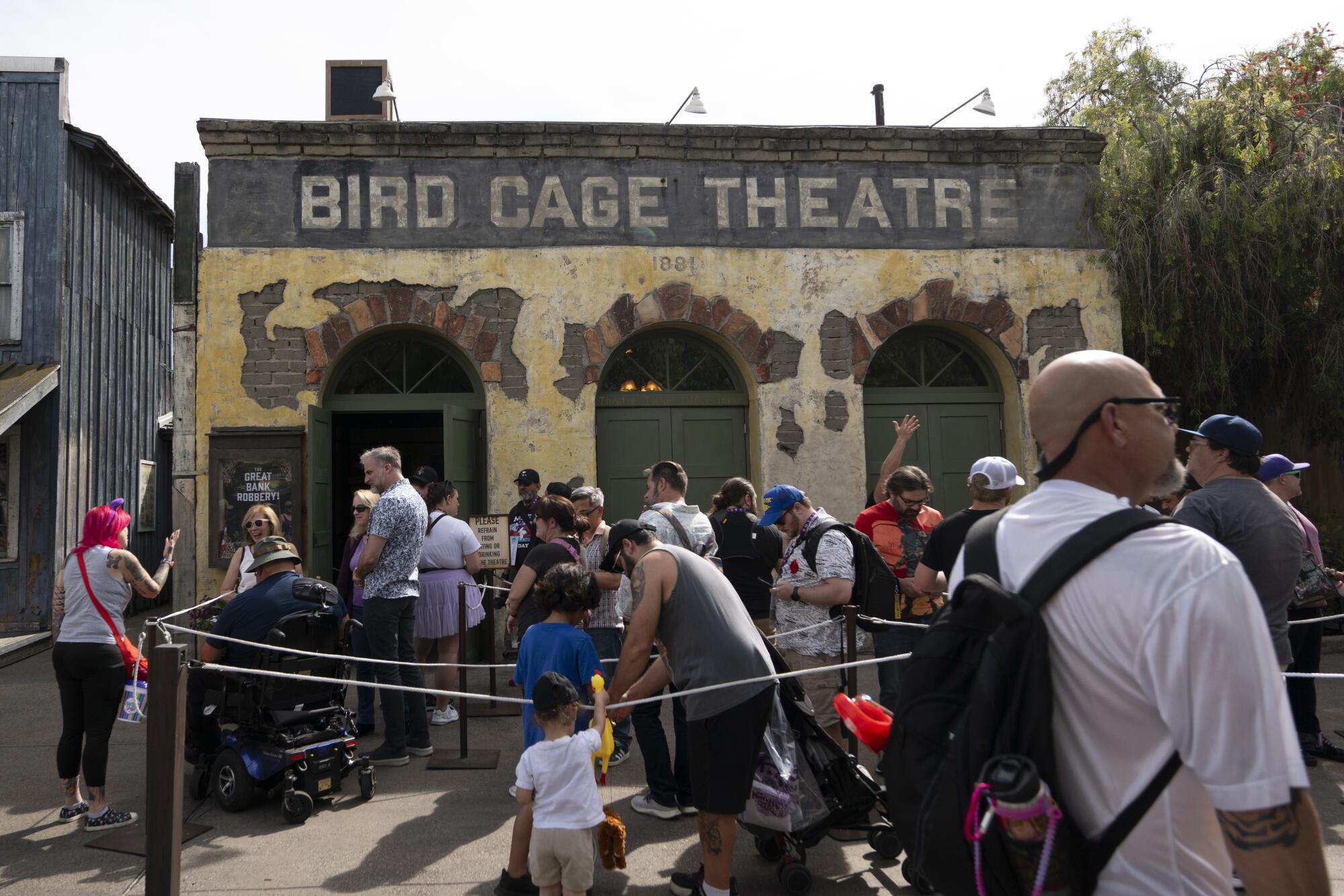 A theater facade with a group of people waiting to get in. 