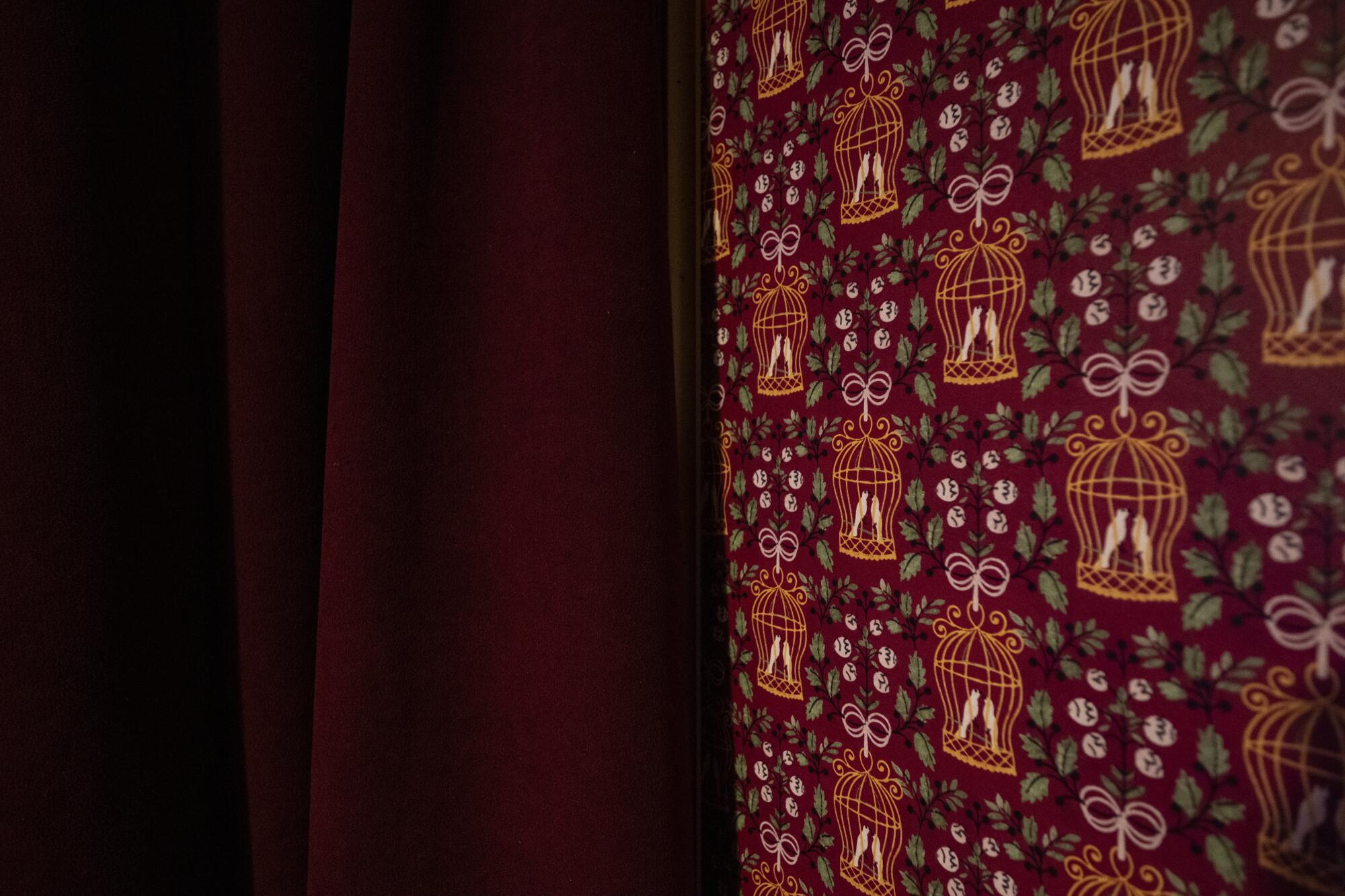 A close-up of red wallpaper featuring flowers and bird cages.