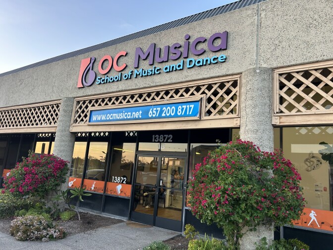 Storefront of a building. A light fixture in front reads, "OC Musica School of Music and Dance."